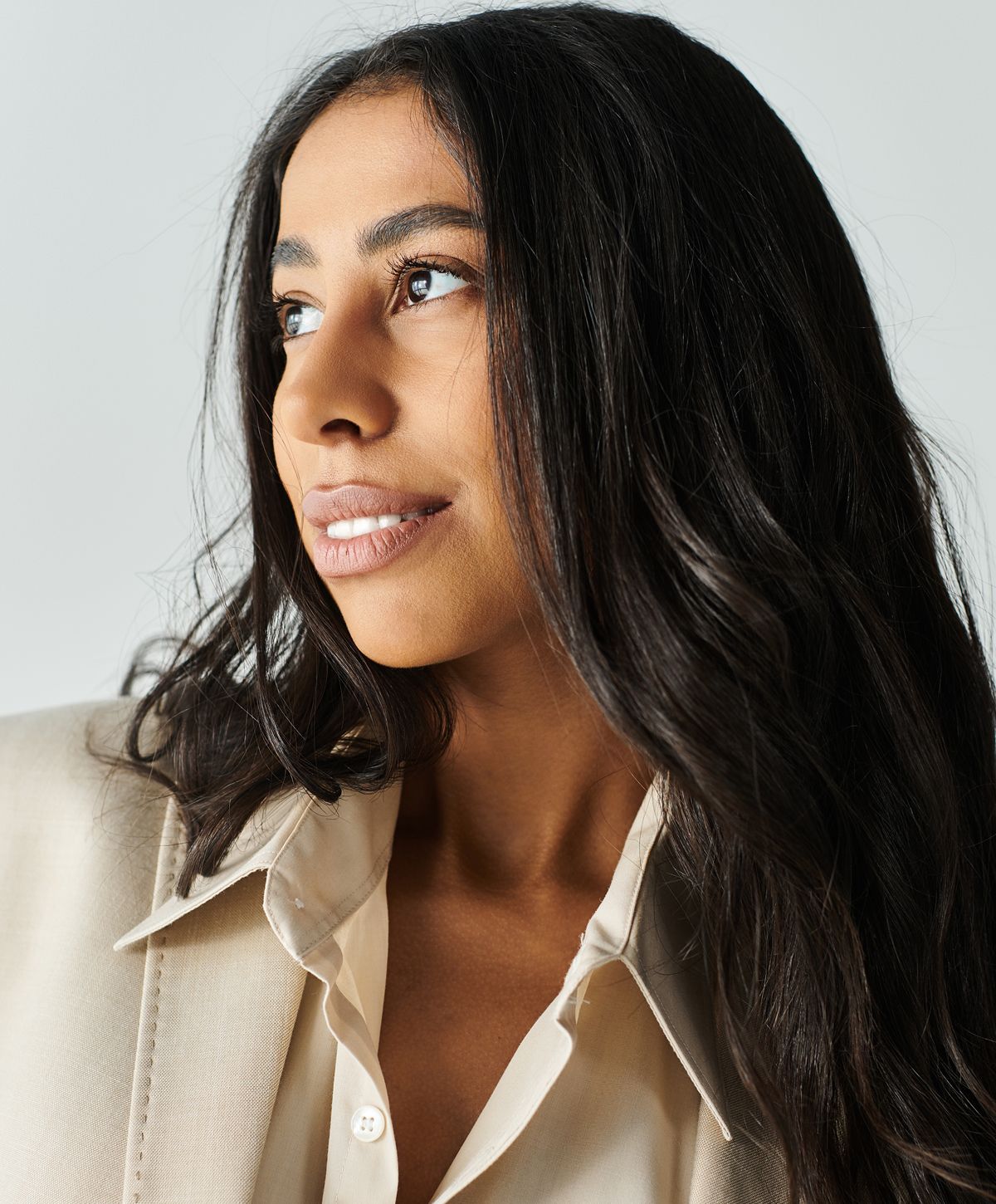 Woman with long hair wearing a beige blazer.