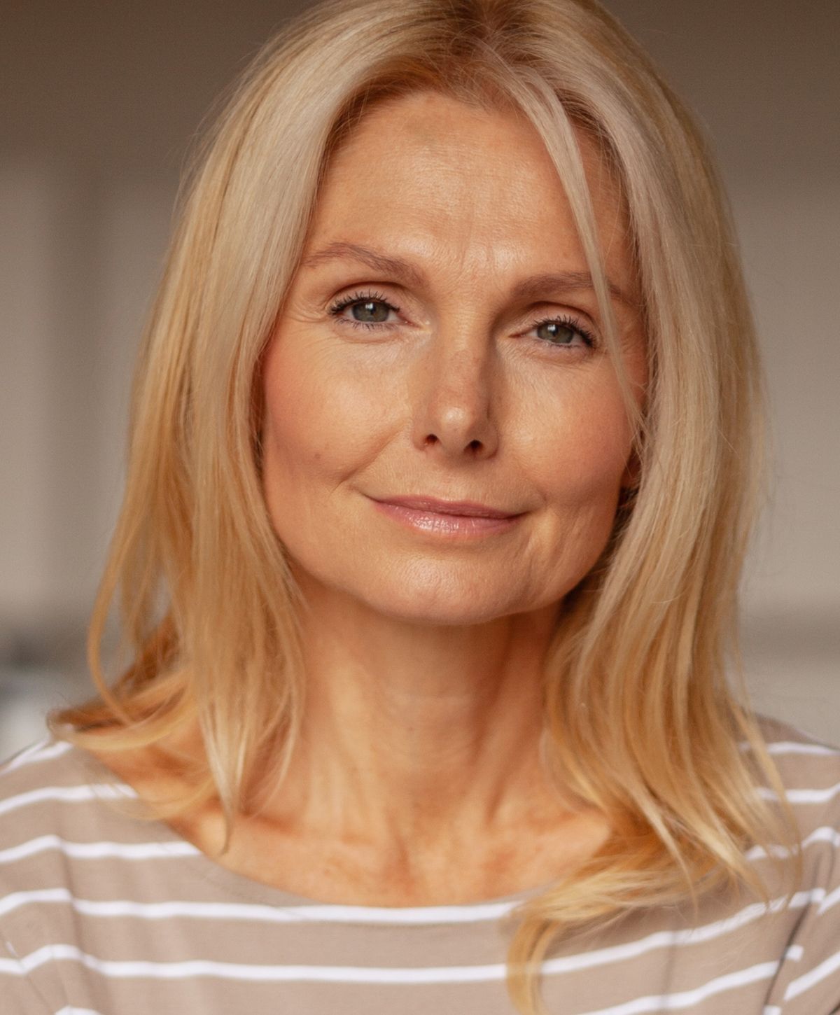Smiling woman with long blonde hair, striped shirt.