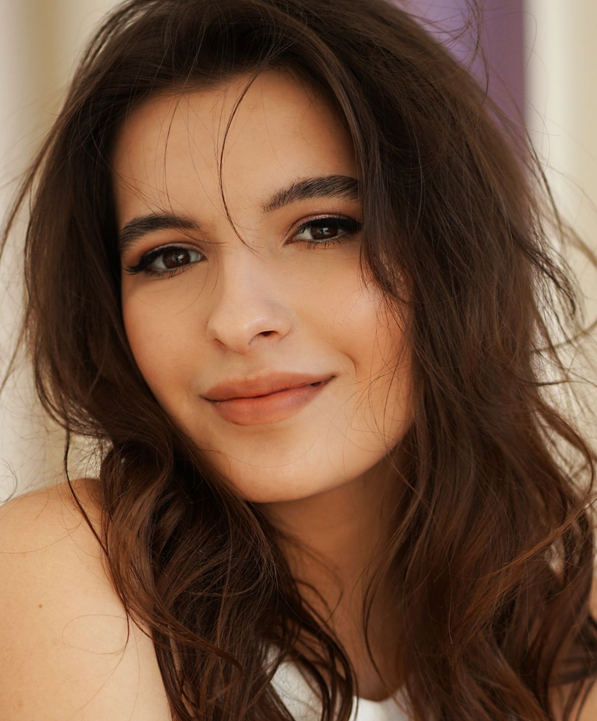 Young woman with long, wavy hair smiling gently.