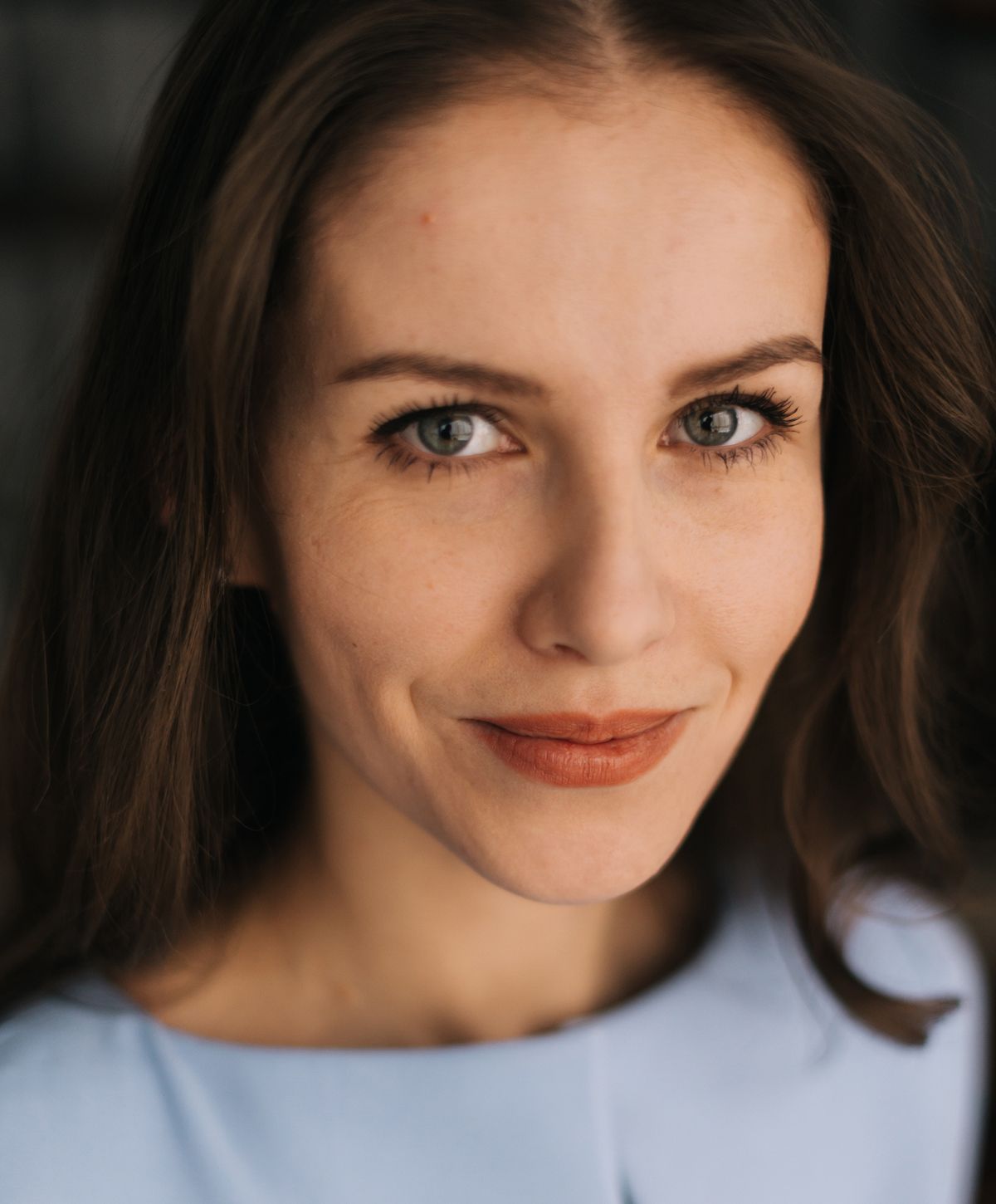 Close-up of a woman smiling, light blue shirt.