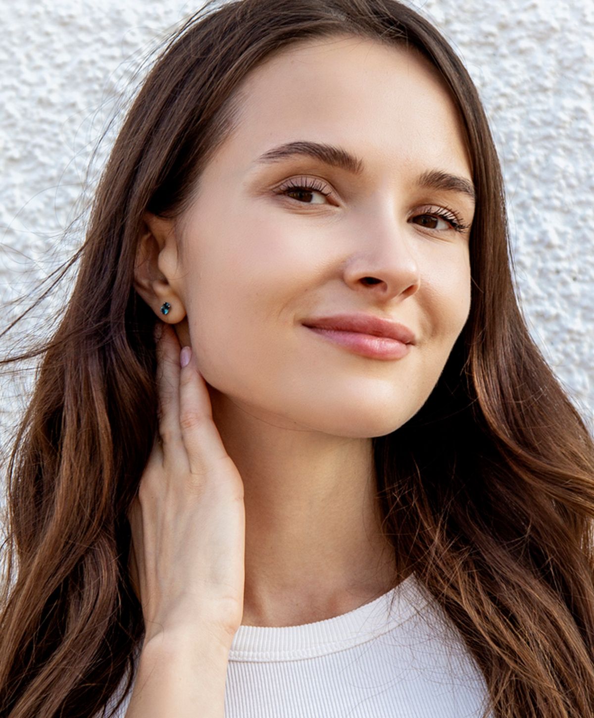 Woman touching her neck, wearing earrings.