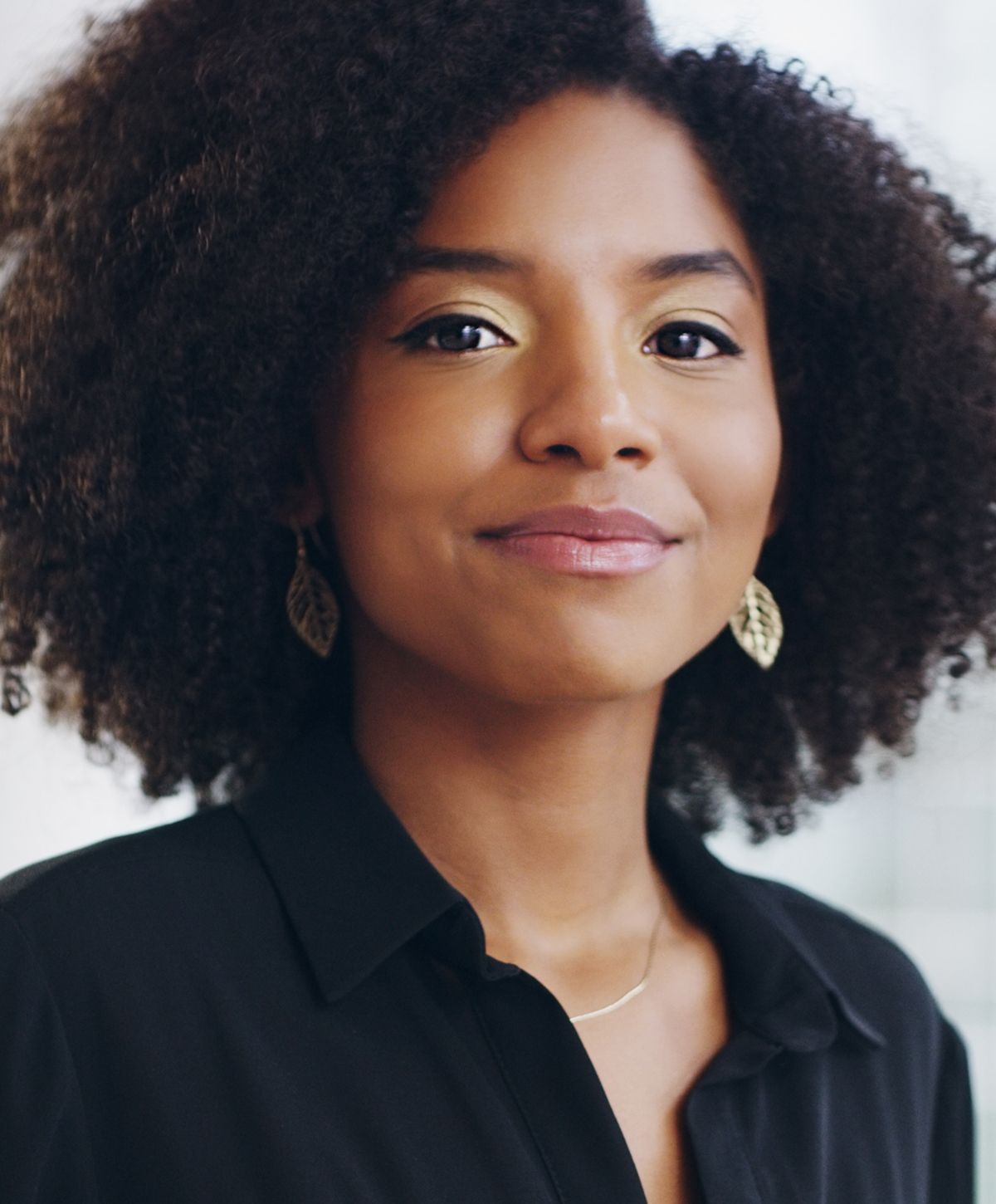 Smiling woman with curly hair and earrings.