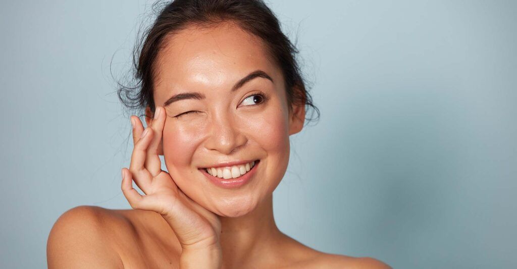 Suffolk, VA Benign Mole Removal model winking against blue background.