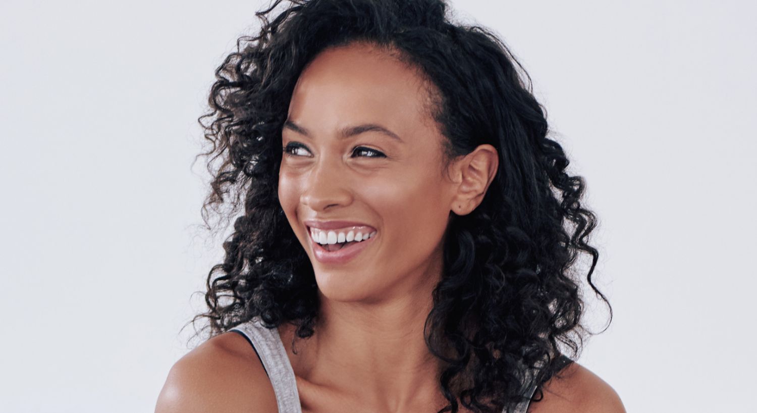 Smiling woman with curly hair and joyful expression.