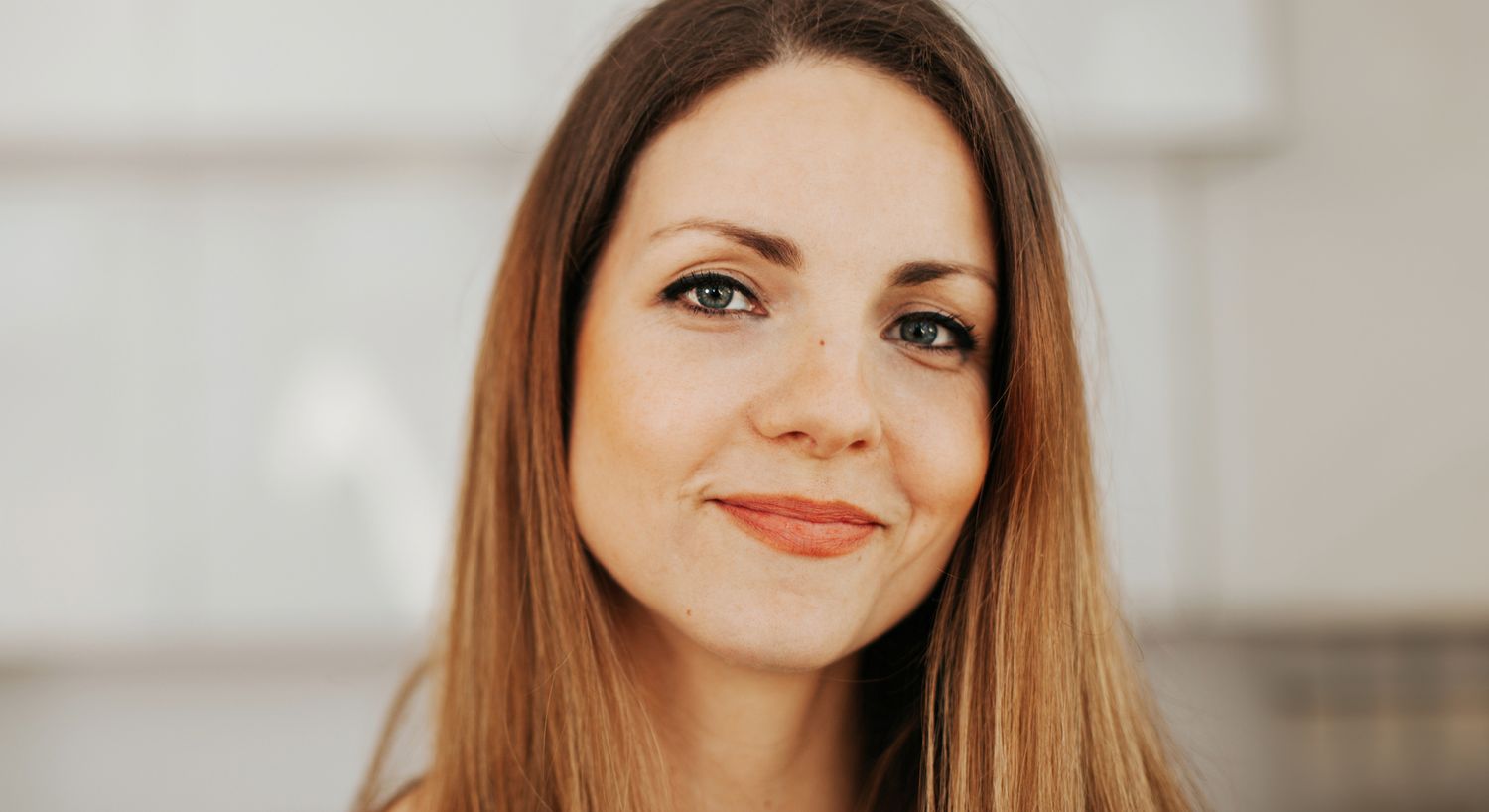Smiling woman with long hair and natural makeup.