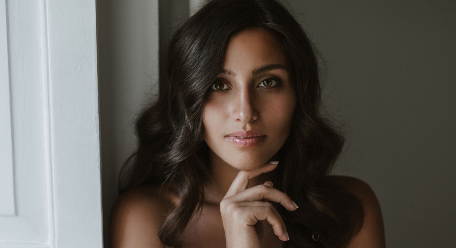 Young woman with long hair resting her chin.