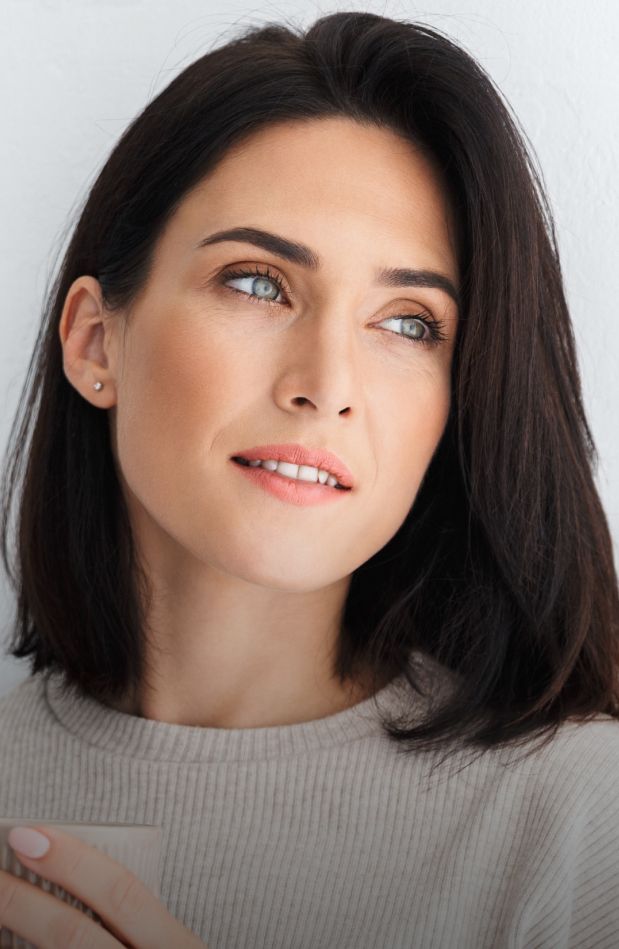 Woman with dark hair looking thoughtfully to side.