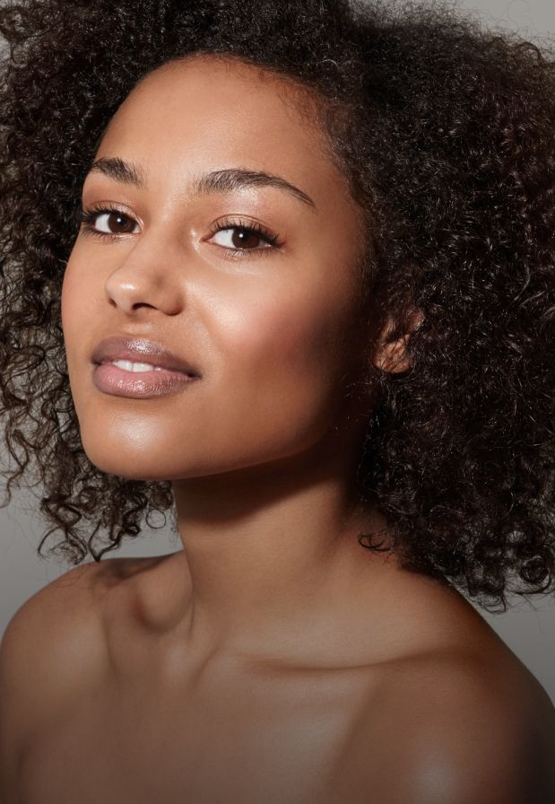 Woman with curly hair posing confidently.