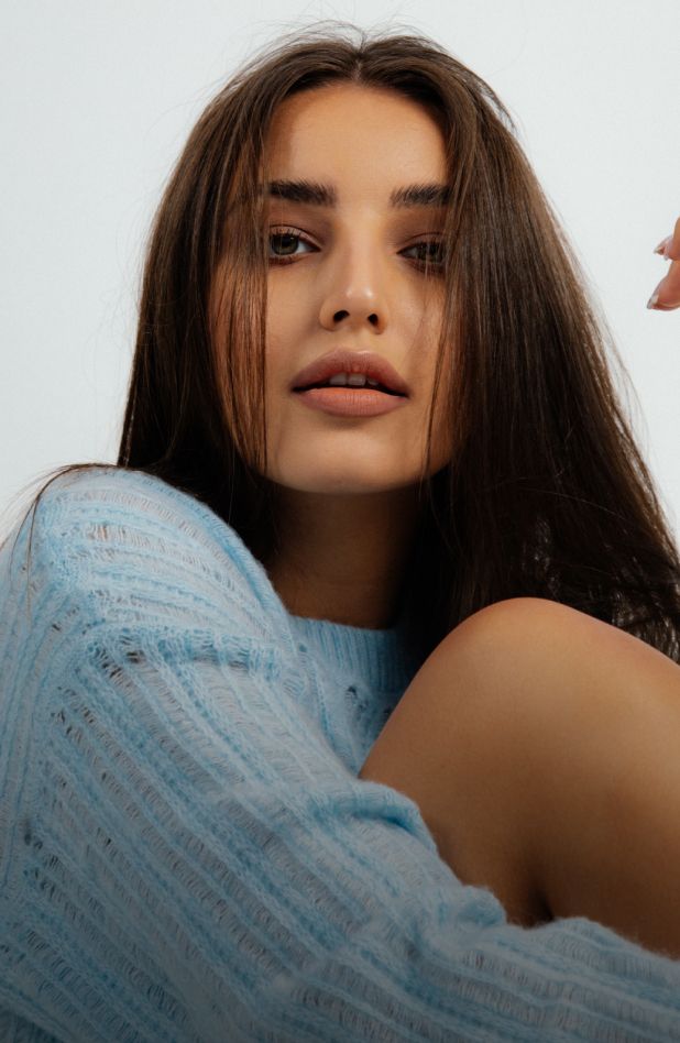 Young woman in blue sweater, looking at camera.