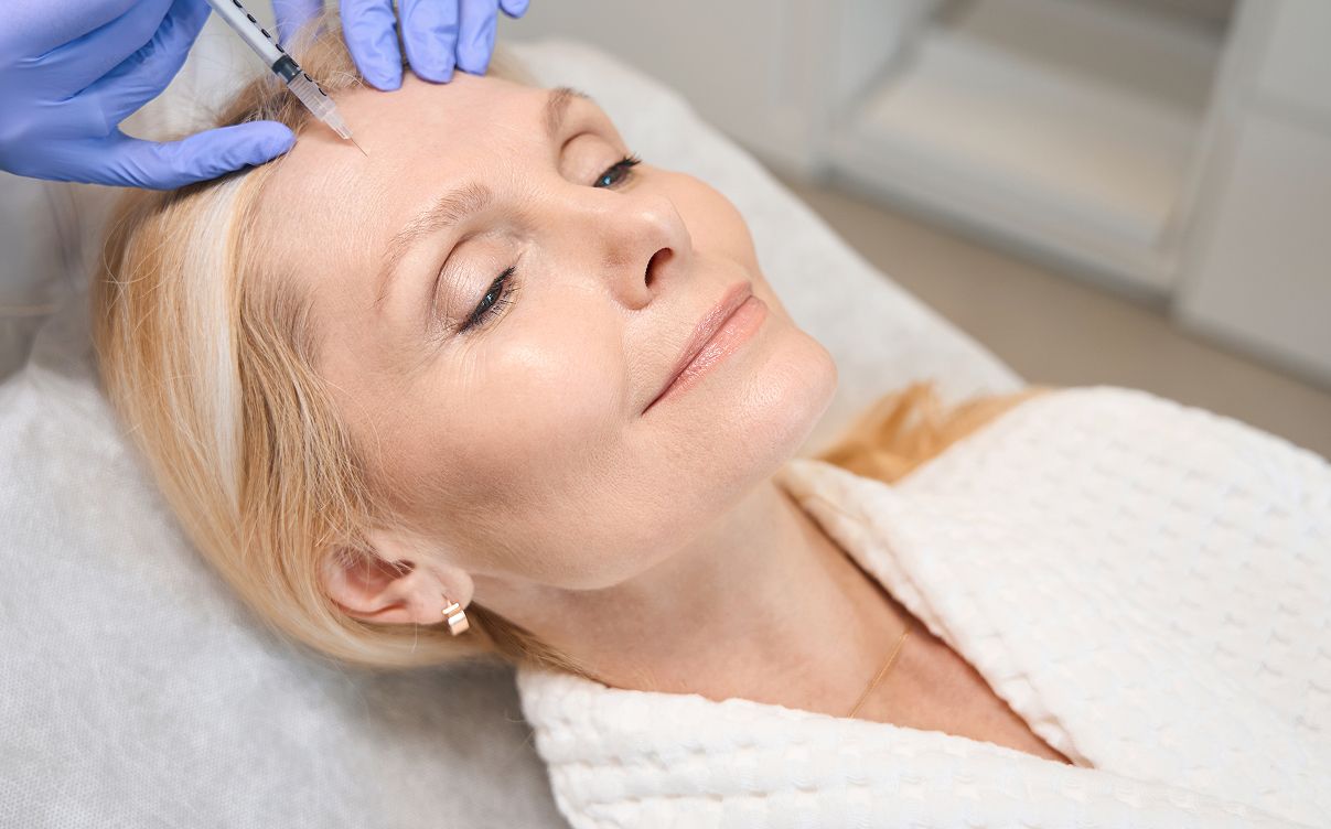 Woman receiving cosmetic treatment with syringe.