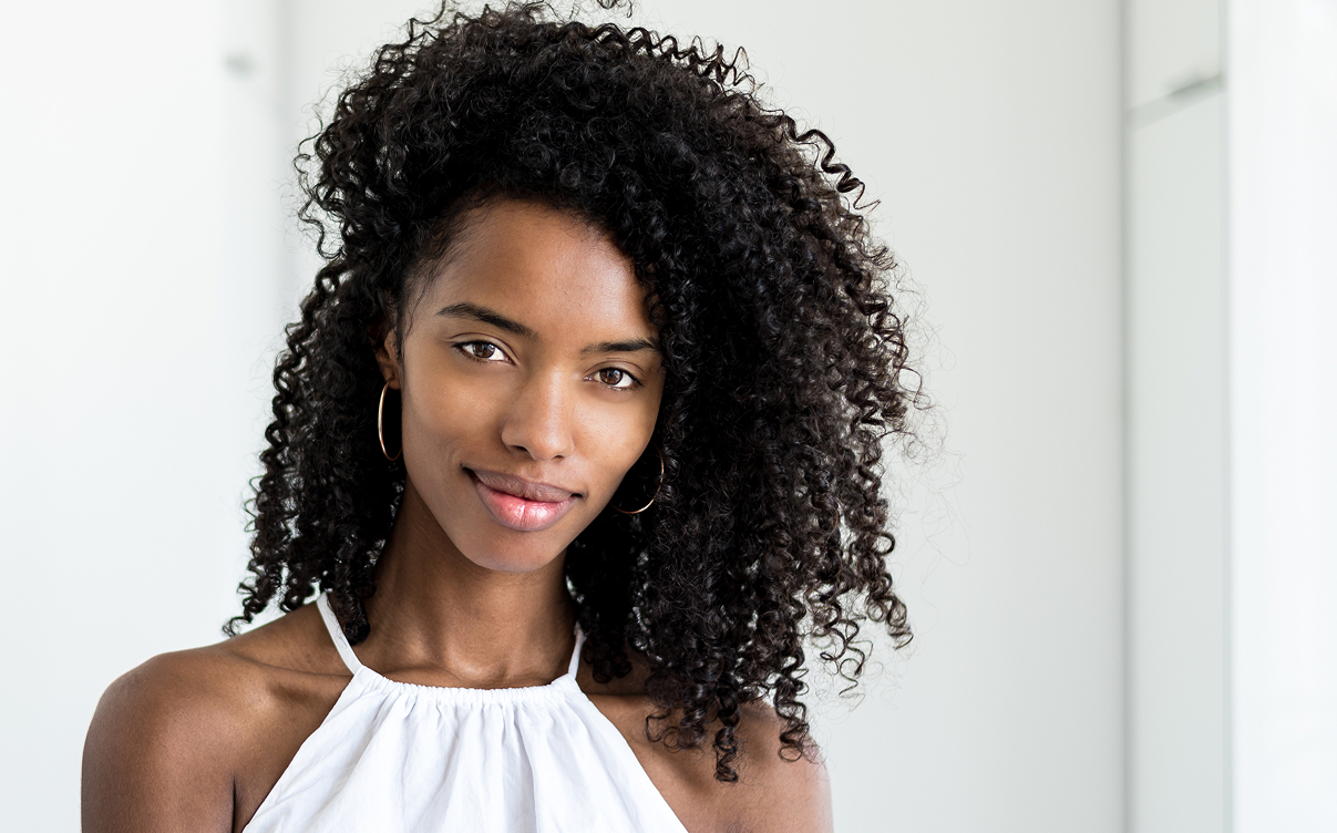 Young woman with curly hair, smiling softly.